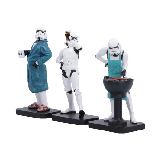 Three Star Wars Stormtrooper figurines posed in everyday scenarios: one in a blue robe holding a mug, one raising a celebratory beer, and one grilling with a teal apron, all on black bases