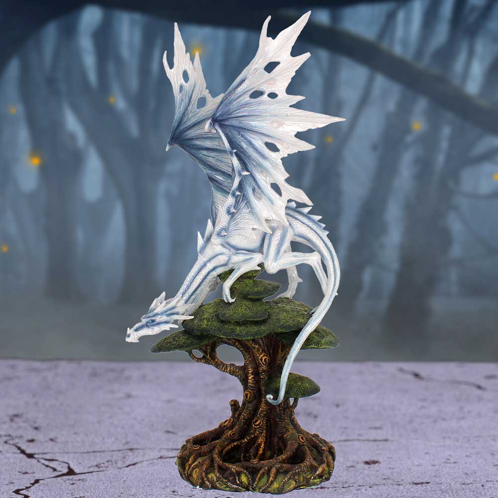 A hand-painted white dragon figurine perched on a tree branch, with detailed wings and a cold, icy appearance, cast in resin from Nemesis Now on display