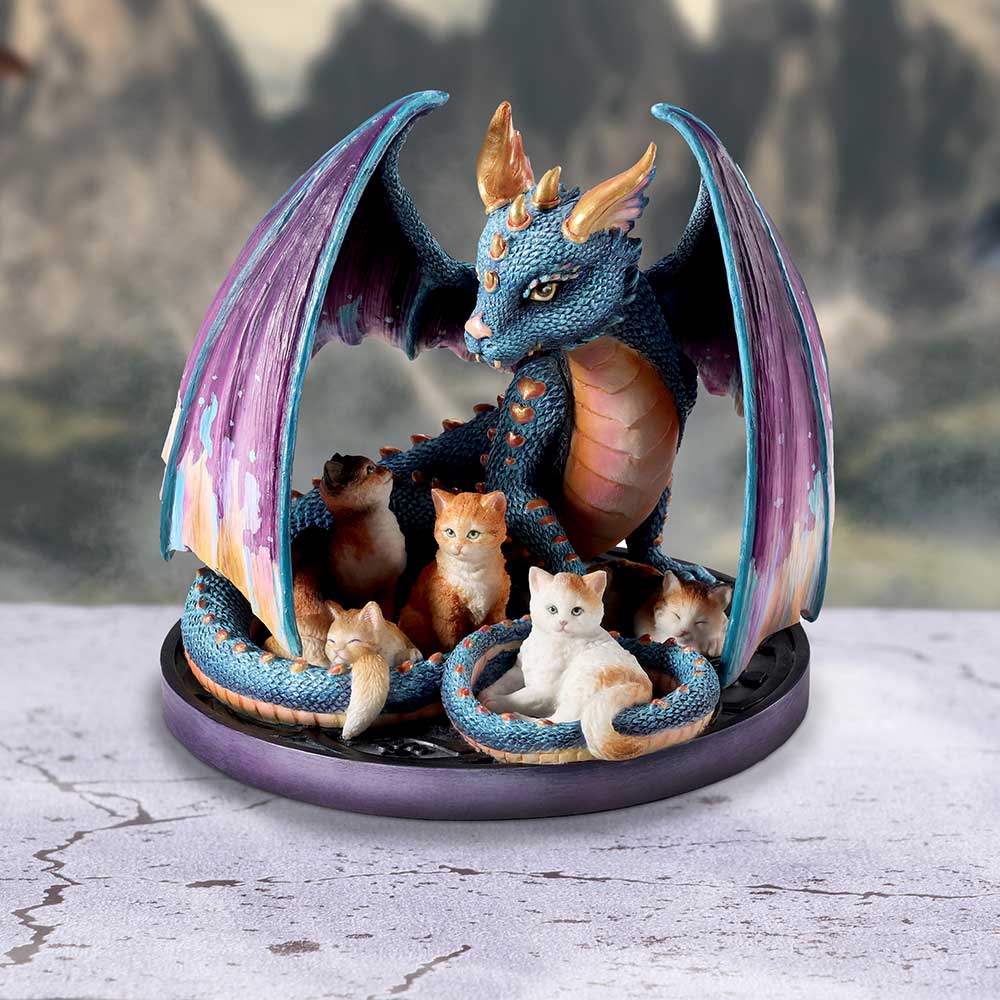 A figurine of a blue dragon with purple wings, sheltering orange and white kittens under its wings on display