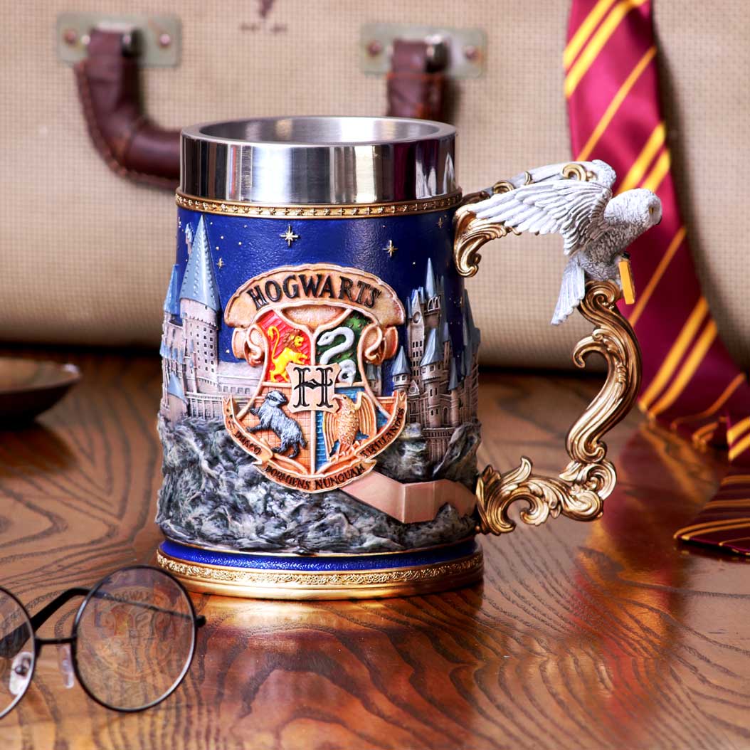 A ceramic Harry Potter Hogwarts collectible tankard featuring the Hogwarts crest and a 3D landscape of the school, along with an image of Hedwig the white owl on the handle on display