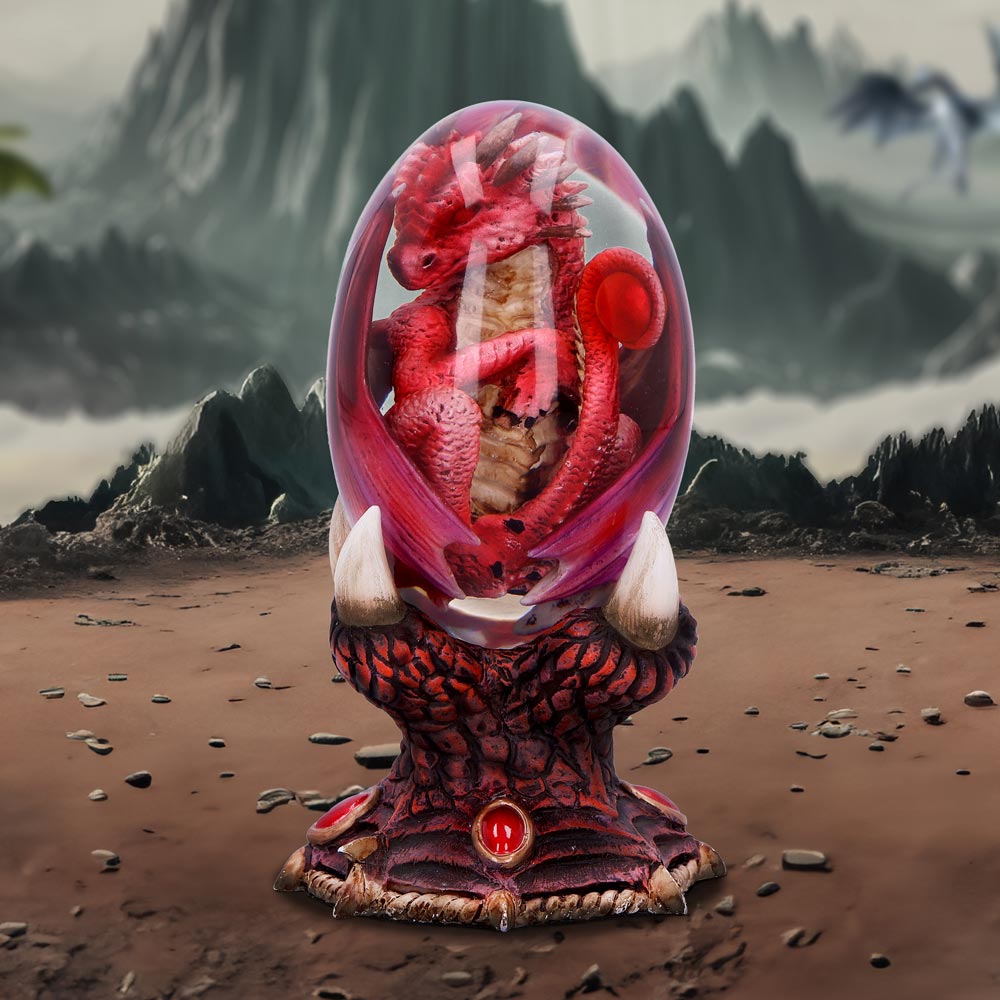 A red fire dragon figurine inside a clear egg, placed on a bronze and red stand, part of the Elemental Dragonlings collection on display
