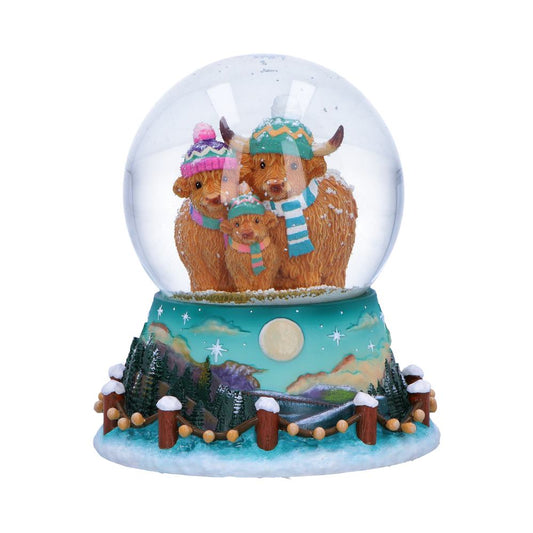 Winter Highland Cow Snow Globe 13.7cm featuring a family of Highland cows wearing colourful hats and scarves beneath a snowy Scottish night sky.