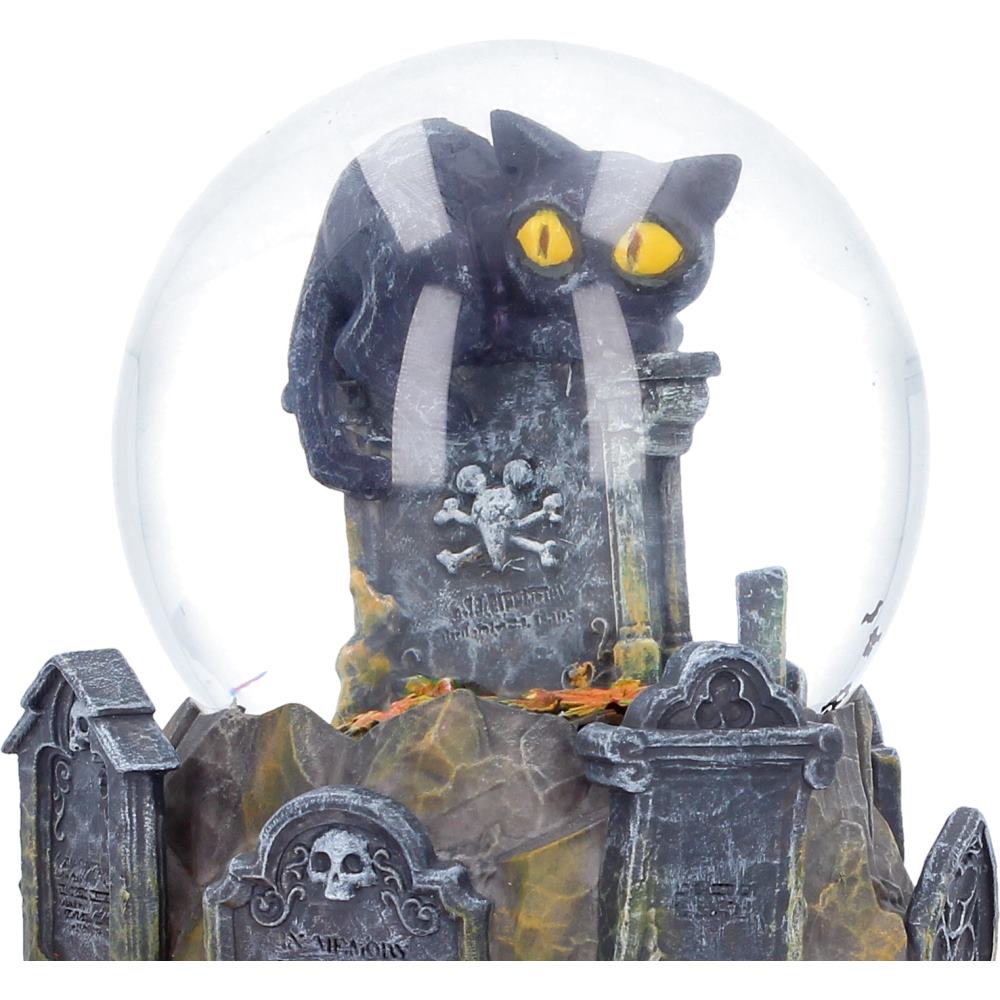 Close-up of black cat with bright yellow eyes inside Pumpkin Patch snow globe