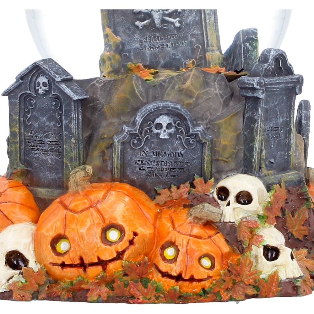 Black cat perched on gravestone inside Pumpkin Patch Halloween snow globe with bright orange pumpkins on the detailed base and creepy skull details