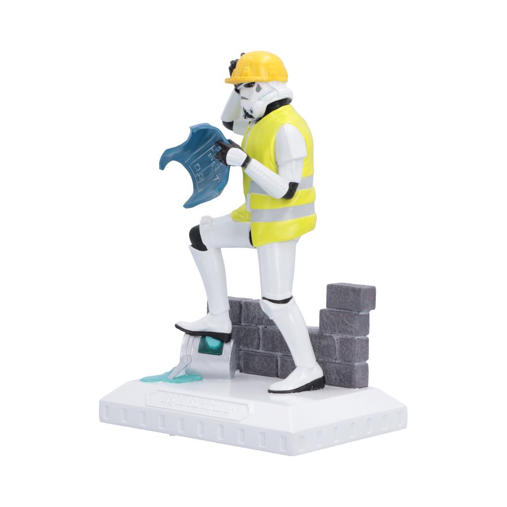 Side view of Hit a Brick Wall a Star Wars collectible figurine of a Stormtrooper dressed as a construction worker, wearing a yellow hard hat and high-visibility vest while holding a blue blueprint, standing on a gray brick platform over a white base.