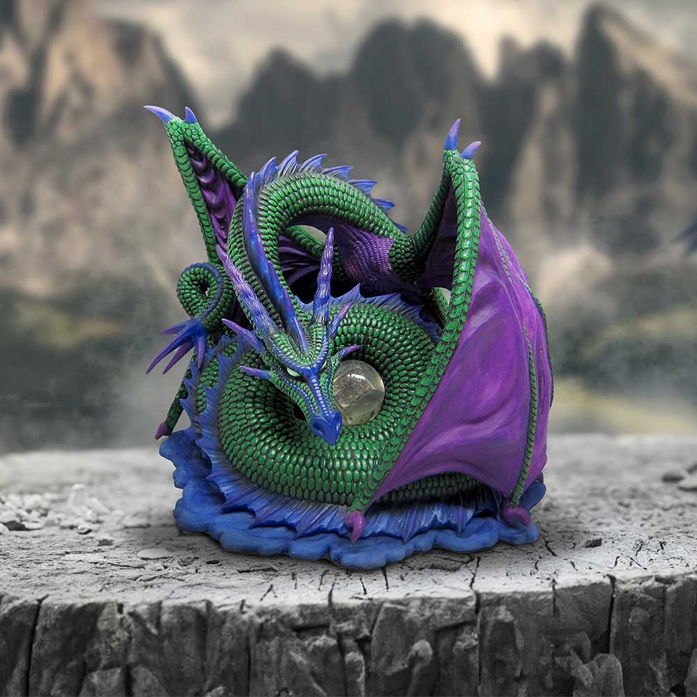 A figurine of a mythical dragon with green body and purple wings, designed by Derek W Frost, curled protectively around a translucent gemstone on display
