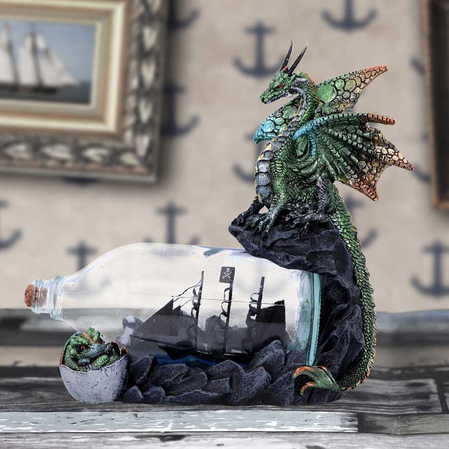 A 22cm figurine of a green dragon sitting atop a rock with a glass bottle beneath containing a black pirate ship. A small dragonling is depicted at the neck of the bottle on display