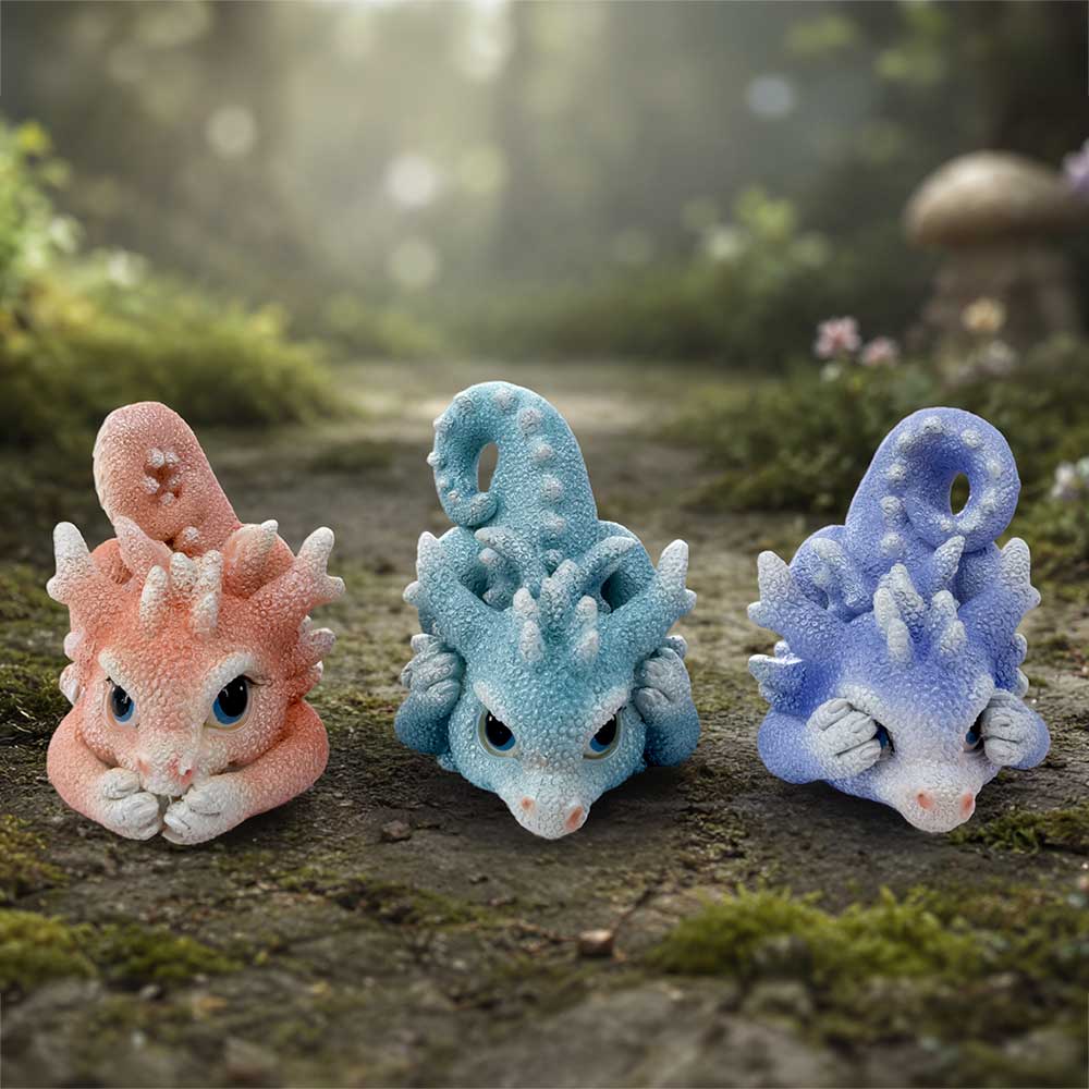 Three Wise Coralscale Dragonlings fantasy dragon set for collectors. The left dragon is peachy pink, the center one is light blue, and the right one is lavender-blue on display.